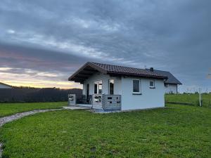 a small white house in a grassy field at Domki Me Mazury in Giżycko