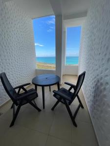 a table and two chairs in a room with a view of the ocean at Bel appartement avec piscine vue mer & golf in Asilah