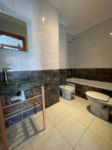 a bathroom with a sink and a toilet and a tub at Bel appartement avec piscine vue mer & golf in Asilah