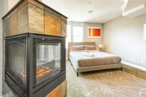a bedroom with a large fireplace next to a bed at Iconic Downtown Colorado Springs Penthouse with 2000 Sq Ft Rooftop Deck, 10 Person Hot Tub and Stunning Mountain Skyline Views, Two Fireplaces, and Two Lavish Primary Suites in Colorado Springs