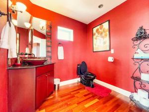 a red bathroom with a sink and a toilet at Iconic Downtown Colorado Springs Penthouse with 2000 Sq Ft Rooftop Deck, 10 Person Hot Tub and Stunning Mountain Skyline Views, Two Fireplaces, and Two Lavish Primary Suites in Colorado Springs +30 photos