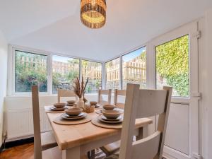 a dining room with a table and chairs and windows at Darla Cottage in Thornton Dale