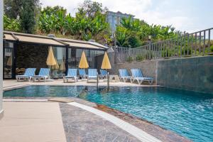 a swimming pool with blue chairs and umbrellas at İnci suites & Tatil Evleri in Alanya