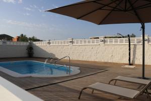 a swimming pool with an umbrella and two chairs and a table at Villa Calatrue - Tabernas in Tabernas