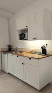 a kitchen with white cabinets and a microwave at Studio Lysandre in Saint-Ambroix
