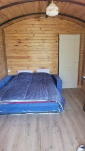 Cama azul en habitación con pared de madera en Magnifique roulotte, en Sospel