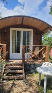 Cabaña de madera con porche y mesa en Magnifique roulotte, en Sospel
