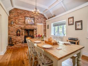 a dining room with a wooden table and a fireplace at Miners Arms Cottage in Stepaside