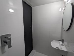 达卡Minimalist Apt at DAC Intl Airport Msg to Avail Special Offer for Flight Catcher的带水槽和镜子的白色浴室