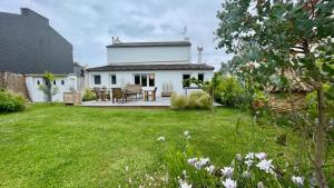 a white house with a patio and a yard at Ty Leroux - wifi - centre bourg in Crozon