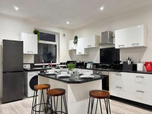 a kitchen with white cabinets and a island with bar stools at 3 BD Luxury Stay For Contractors & Families in Newcastle upon Tyne