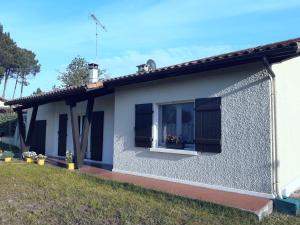 a white house with black shutters and a window at La Maison LEON in Ychoux