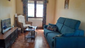 a living room with a blue couch and a tv at La Maison LEON in Ychoux