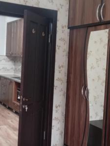 une armoire en bois dans une cuisine avec un miroir dans l'établissement A cozy corner im Saburtalo 3, à Itʼkhvisi 1 autre photo