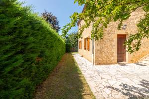 Un seto al lado de un edificio con una pasarela. en Entre 2 Jardin Drap compris et Barbecue, en Sarlat-la-Canéda