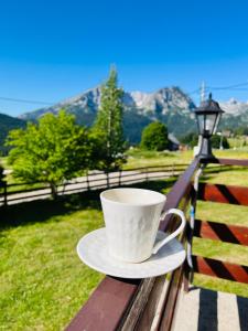 a coffee cup sitting on a bench with a view of mountains at DURMITOR APARTMAN Pitomine in Žabljak