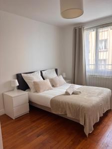 une chambre avec un lit avec des draps blancs et une fenêtre dans l'établissement Charmant T3 Vue Mer & Confort en Plein Centre, à Brest