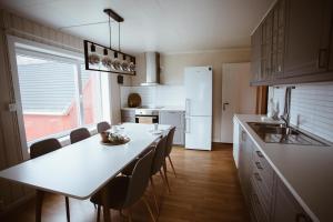 a kitchen with a table and chairs and a white refrigerator at Beach apartment with unique view in Ervik