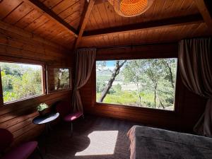a room with two large windows in a wooden cabin at The Bungalow - Quinta da BellaVista in Almoster