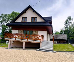 a small house with a porch and a staircase at Między Górami in Korbielów