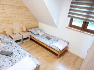 two beds in a room with wooden walls at Między Górami in Korbielów