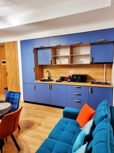 a living room with a blue couch and a kitchen at Alpin Confort Predeal in Predeal