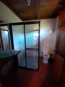 een badkamer met een toilet en een glazen douchecabine bij La Puerta de Malacatiupan in Atiquizaya