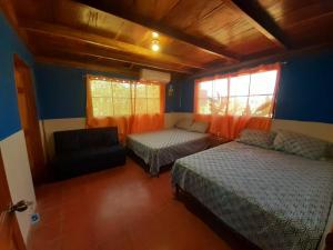 een slaapkamer met twee bedden en een bank en een raam bij La Puerta de Malacatiupan in Atiquizaya