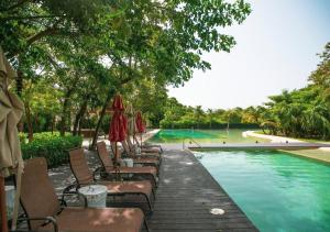 a swimming pool with chairs and umbrellas next to a pool at Corasol Condo with Rooftop Pools, Beach Club Access & Private Terrace in Playa del Carmen