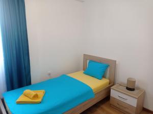 a small bedroom with a bed with blue and yellow at Apartment Tamara in Tivat