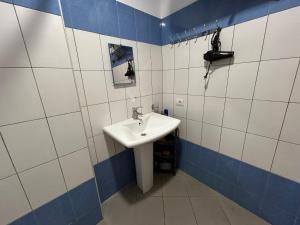 a bathroom with a white sink and blue and white tiles at Duplex on Fifth in Sarandë