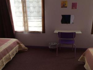 a room with two beds and a table and a chair at Hôtel La Fontaine in Lourdes