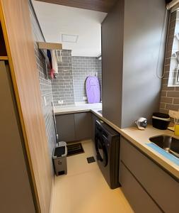 a small kitchen with a washer and dryer at Seu apê de férias - Praia Grande in Praia Grande
