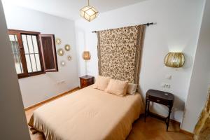 Un pequeño dormitorio con una cama y una silla. en Puerta Romana, en Carmona
