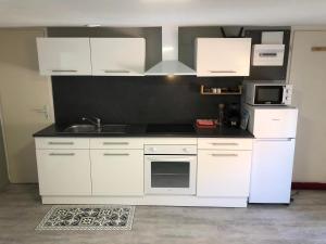 eine Küche mit weißen Schränken und einer Spüle und einer Mikrowelle in der Unterkunft Calme et confort, avec 2 lits ,à la frontière in Audun-le-Tiche + 17 Fotos
