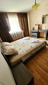 a large bed in a bedroom with a window at Зара Апартамент in Stara Zagora