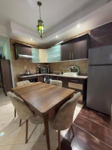 a kitchen with a wooden table with chairs and a refrigerator at Résidence jawharat mogador in Essaouira