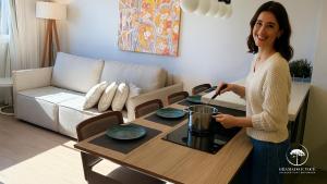 a woman standing next to a table in a living room at Modern apt next to Criamigos Park + coffee Day 1 in Gramado