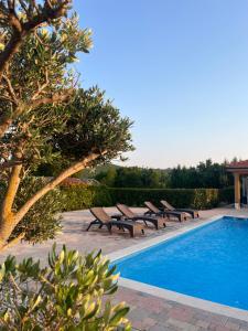 a swimming pool with benches next to a resort at Luxury Villa ROYAL in Ljubuški