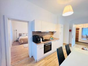 a kitchen with white cabinets and a table and a bed at Modern New Eggenberg Top 1b in Graz
