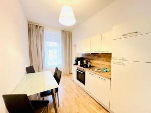a kitchen with white cabinets and a table with chairs at Modern New Eggenberg Top 1b in Graz +18 photos