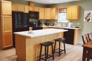 a kitchen with a black refrigerator and a counter with stools at Lakeshore Lodging Apartment G in Homer