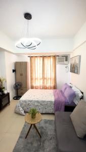 ein Schlafzimmer mit einem Bett, einer Couch und einem Tisch in der Unterkunft Avida Towers Riala IT PARK Cozy Studio in Cebu City