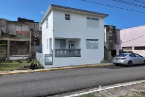 a white house with a car parked on the street at VSS La Puntilla in Arecibo - Stylish Coastal Getaway in Arecibo