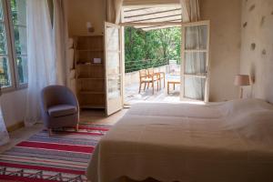1 Schlafzimmer mit einem Bett und einem Stuhl sowie einer Terrasse in der Unterkunft Le Clarou in Valleraugue