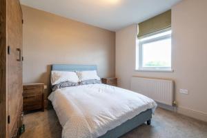 a bedroom with a bed with a blue headboard and a window at Cartercroft, Sheffield in Sheffield