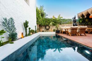 Una piscina con sillas y una mesa al lado de una casa. en Karnelyan Alaçatı, en Cesme