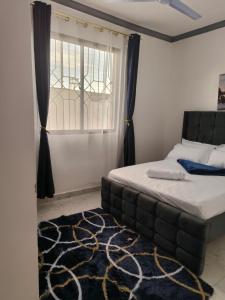 a bedroom with a bed and a window and a rug at Mama Abayi Fakhi in Mombasa