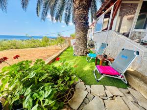 two chairs sitting on the grass next to a house at BLUE PANORAMA DIAMOND with Amazing Sea View in Makri