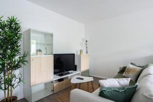 een woonkamer met een bank en een tv bij Horizon Paisible - Piscine et parking ! in Toulouse